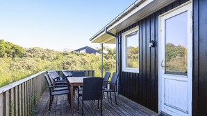 Eine Terrasse mit Gartenmöbeln, einer Tür und Blick auf einen Hügel.