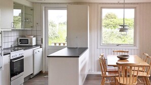 Eine moderne Küche mit weißen Schränken, einer eingebauten Mikrowelle, einem Backofen und einem Essbereich mit Holztischen und -stühlen.