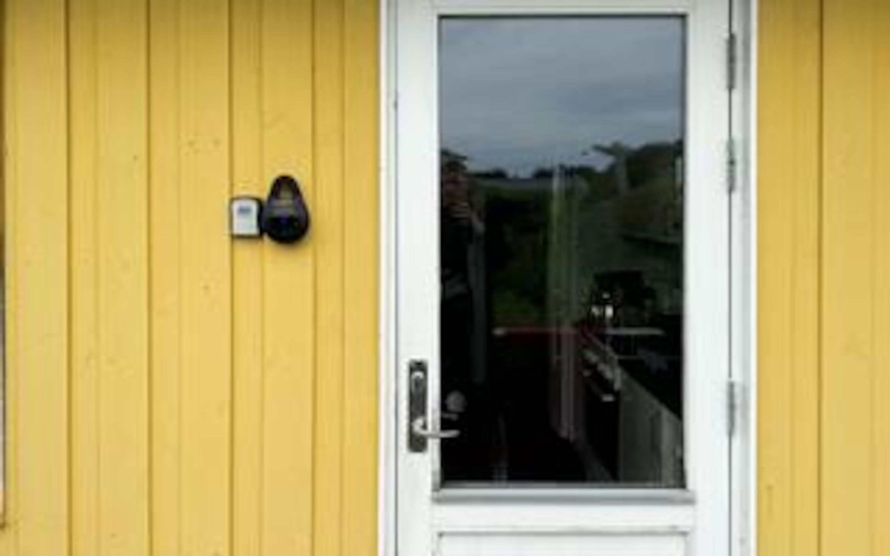 Un edificio amarillo con una puerta blanca y un pequeño buzón en la pared.