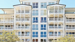 Un hôtel à plusieurs étages, doté de balcons, de grandes fenêtres et d’une façade symétrique.