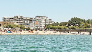 Un hôtel en bord de mer, avec plusieurs étages, une plage au premier plan et un ciel dégagé.