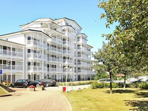 A multi-story hotel with balconies, a parking area, and a landscaped garden. - Holiday Home in Grossenbrode (Grossenbrode)