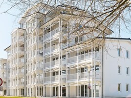 Un edificio de varios pisos con balcones y fachada blanca.