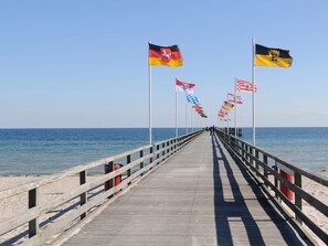 A pier with a wooden walkway leading to the sea, flanked by flags of various countries. - Holiday Home in Grossenbrode (Grossenbrode)