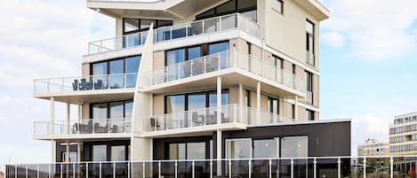 Un edificio de varios pisos con balcones, ventanas amplias y techo plano.