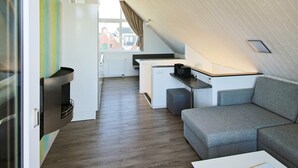 A compact living space with a kitchenette, a sofa, and a dining area. - Holiday Home in Wendtorf (Wendtorf)