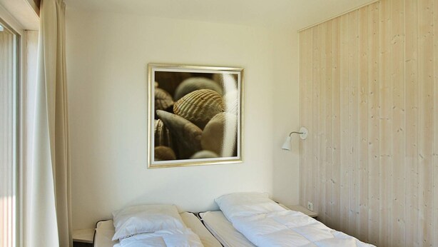 A room with two beds, a wooden wardrobe, a framed picture on the wall, and a window with curtains. - Holiday Home in Wendtorf (Wendtorf)