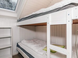 A bunk bed with a skylight above, white walls, and a wooden floor.