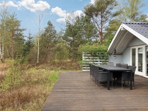 A wooden deck leading to a building with a sloped roof and a glass door.