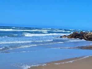 Una playa con olas, rocas y cielo despejado.