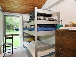 A bunk bed with storage drawers, a wooden dresser, a chair, and a view of a green outdoor area. - 6 Person Holiday Home in Saltum (Saltum)