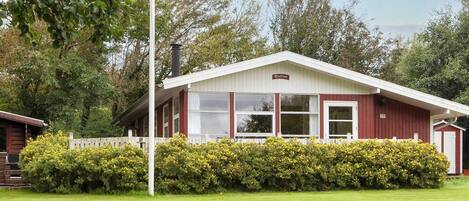 A red and white building with a white fence and yellow flowering bushes in front.