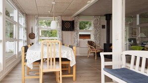 Un coin repas avec une table dressée pour quatre personnes, des chaises en bois et un banc.