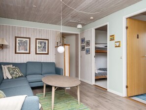 A room with a blue sofa, a small round table, a hanging light fixture, and a wooden door.