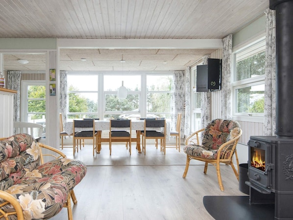 A cozy living room with a fireplace, wooden furniture, and large windows. - 8 Person Holiday Home in Struer (Struer)