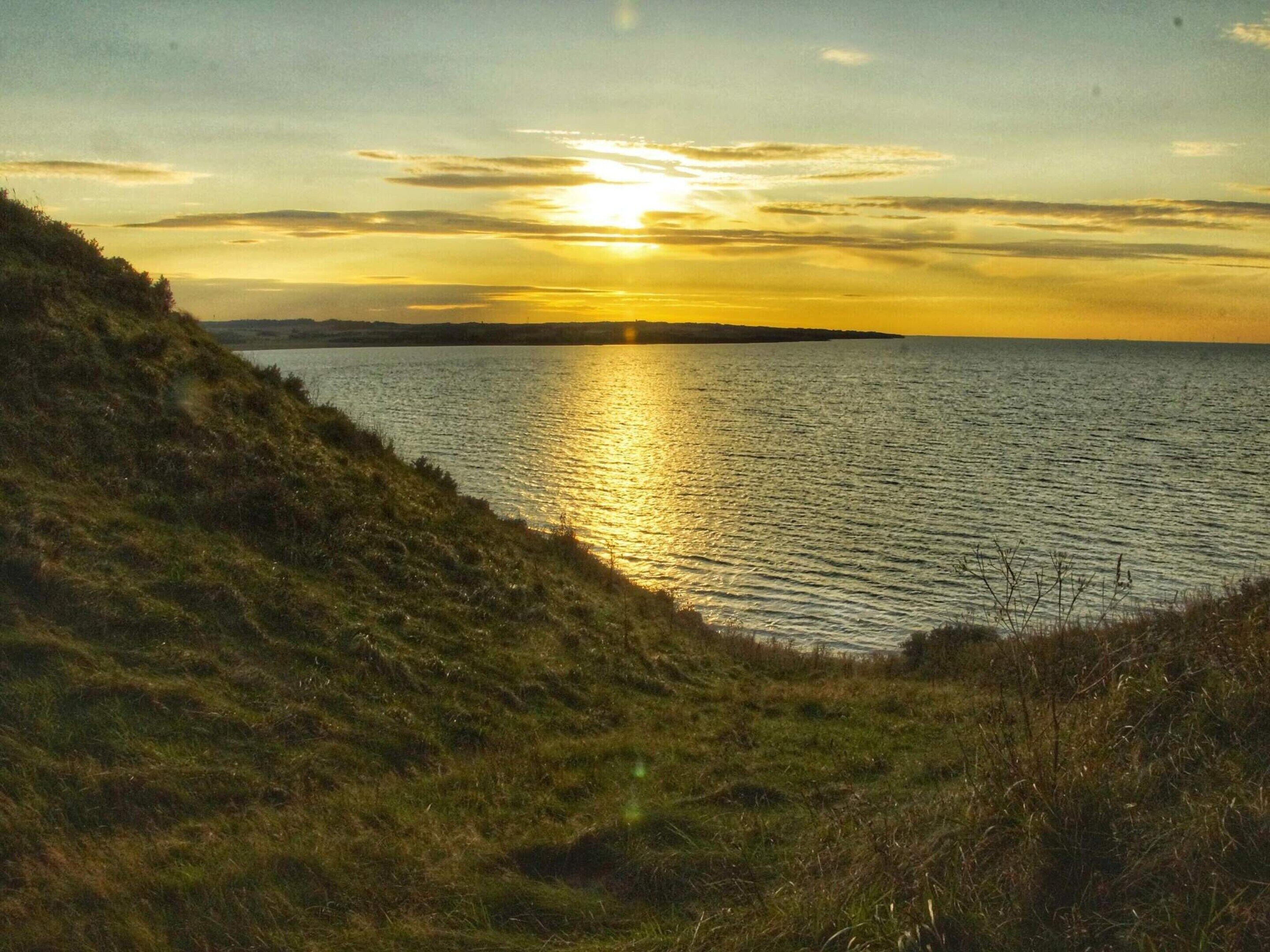 Un paysage côtier avec une étendue d’eau et une colline.