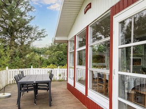 A wooden deck with a table and chairs, a white fence, and large windows. - 8 Person Holiday Home in Struer (Struer)