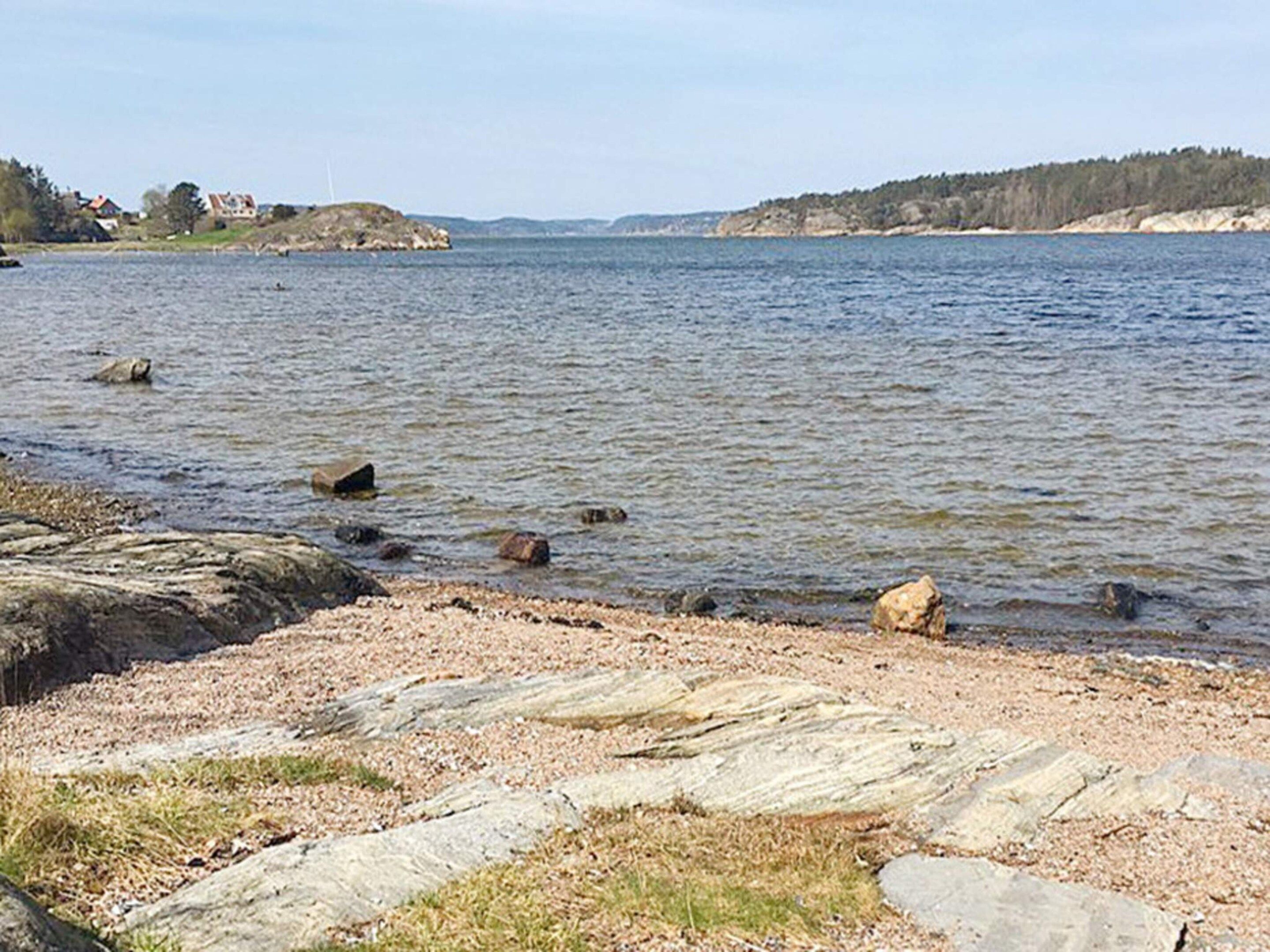 A calm lake with visible rocks and pebbles along the shore.
