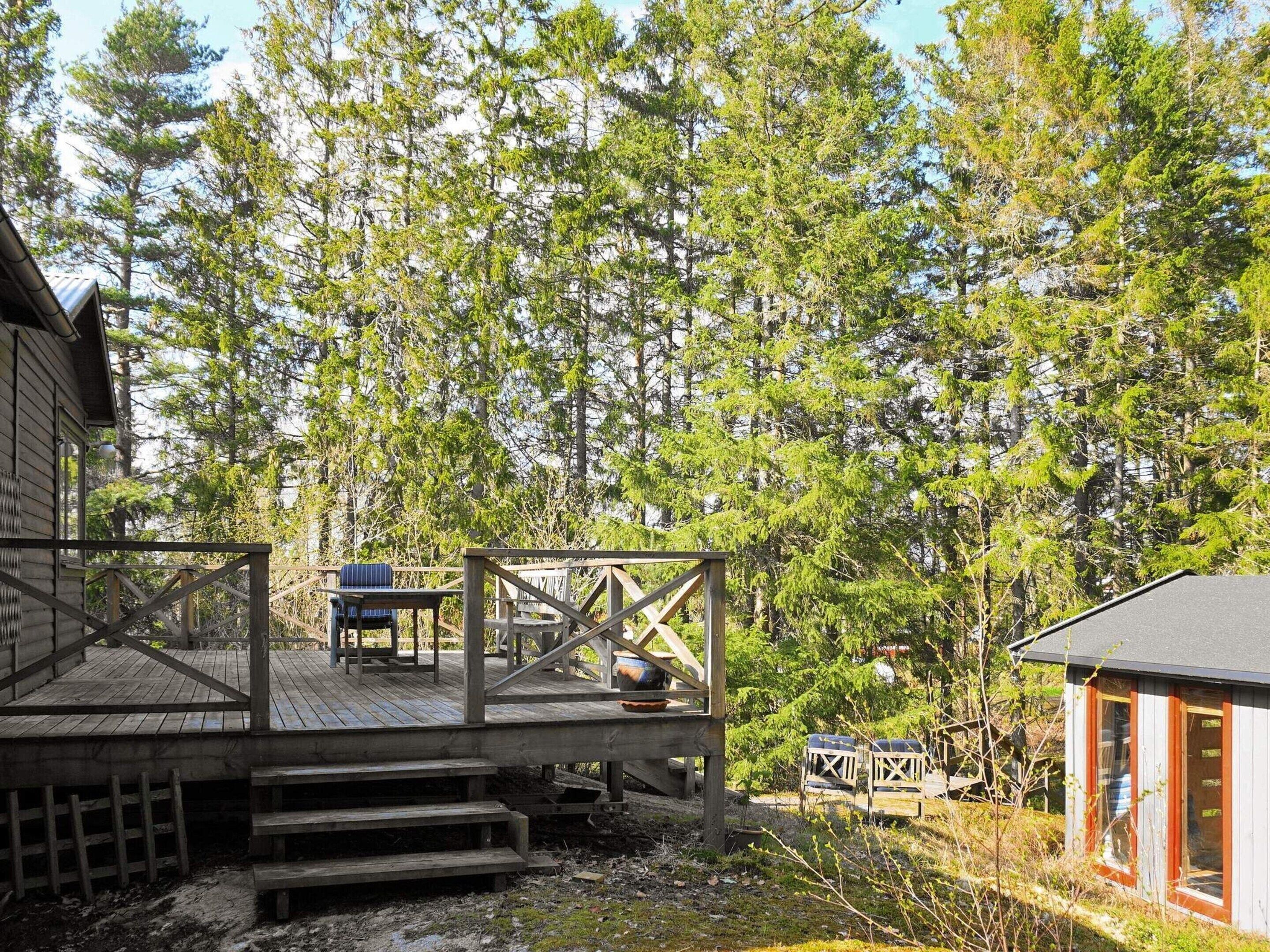 A wooden deck with a table and chairs, overlooking a forested area.