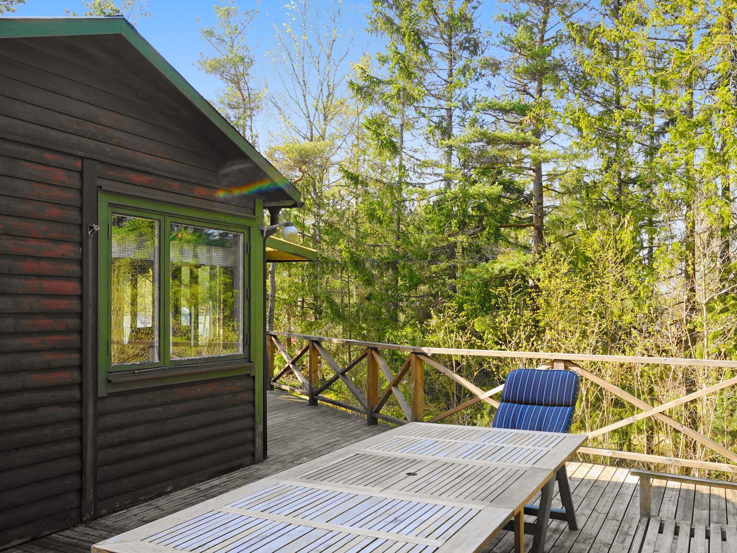 A wooden cabin with a deck, a table, and a chair.
