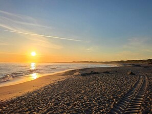 A beach with a visible path leading to the water, a clear sky, and the sun setting or rising. - 5 Star Holiday Home in Thisted (Thisted)