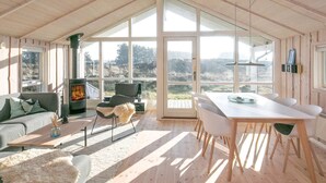 A spacious room with a high ceiling, large windows, a fireplace, a dining area, and a cozy seating arrangement. - 5 Star Holiday Home in Thisted (Thisted)