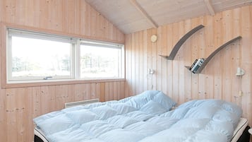 Un dormitorio con cama, ventana y estante en la pared.