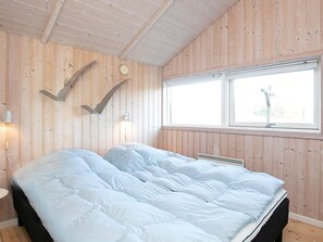 A bedroom with a bed, wooden walls, a window, and a wall-mounted light fixture. - 5 Star Holiday Home in Thisted (Thisted)