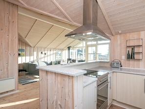 Une cuisine moderne dotée d’un îlot central, de murs en bois et d’une grande fenêtre offrant une vue sur l’extérieur.