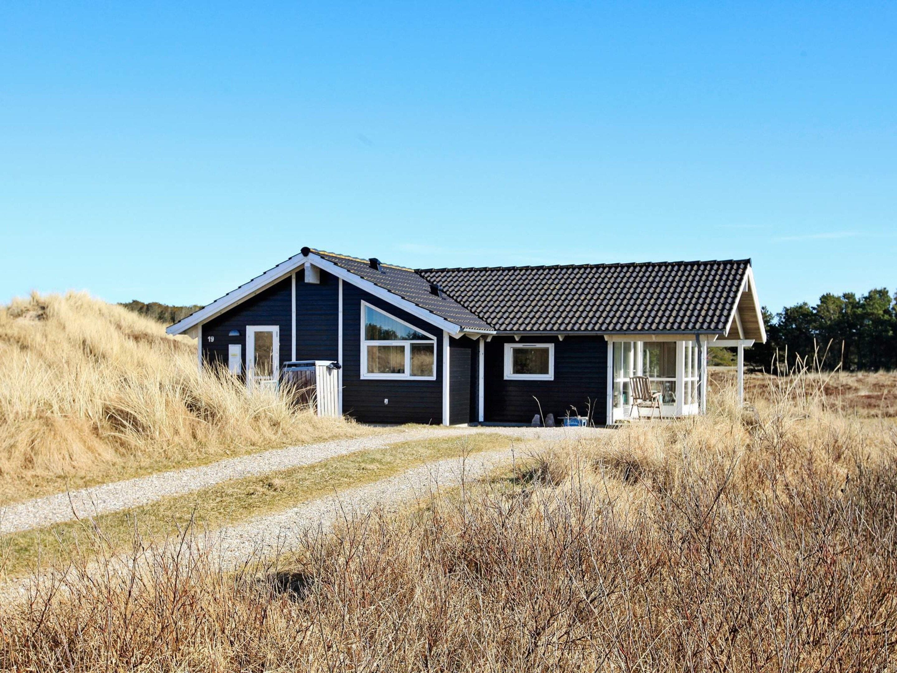 A single-story house with a dark exterior, a sloped roof, and a visible number '19' on the side.