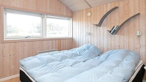 A bedroom with a bed, a window, and wooden walls. - 5 Star Holiday Home in Thisted (Thisted)