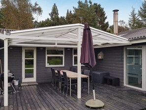 A covered patio with a table and chairs, a grill, and a chimney. - Luxury Holiday Home in Hadsund near Sea (Hadsund)