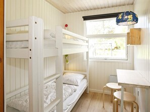 A bunk bed room with a desk and chair, a window with a view, and a hanging lamp.