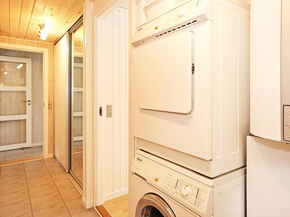 A laundry room with a front-loading washing machine and dryer, wooden flooring, and a door leading to a storage area.