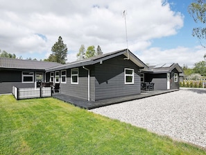 A two-story building with a gravel driveway and a small fenced area.