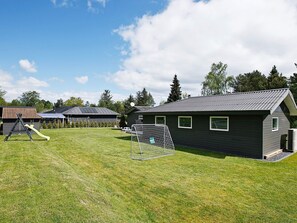 Una propiedad residencial con patio cercado, juegos infantiles y un edificio con techo de metal.