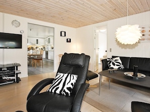 A modern living room with a black leather chair, a black leather sofa, a dining table, and a television. - Luxury Holiday Home in Hadsund near Sea (Hadsund)