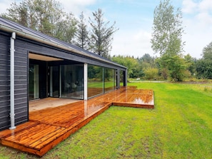 A modern house with a wooden deck and large sliding glass doors.