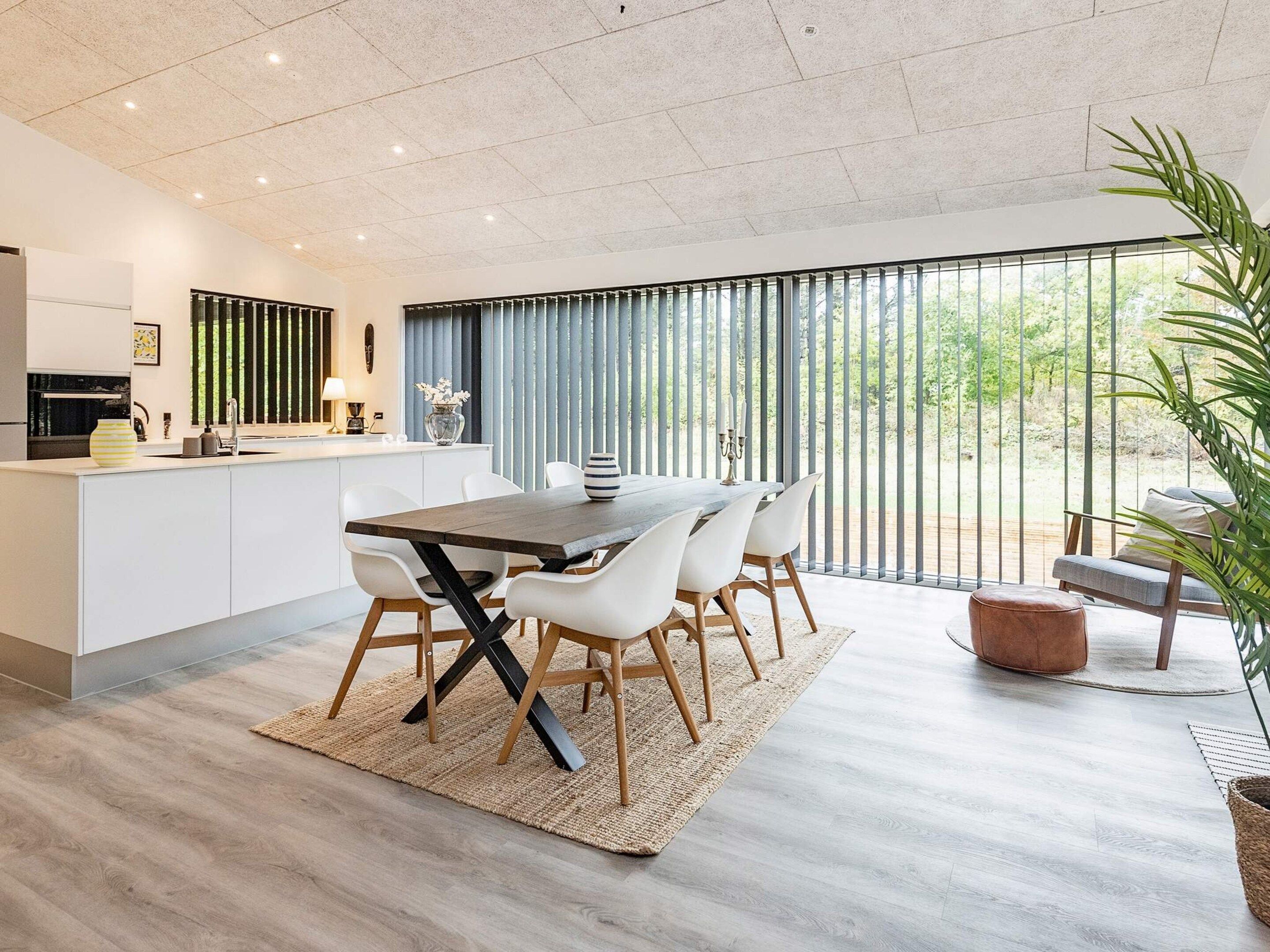 Una cocina moderna con comedor, ventanas amplias y vistas a zonas verdes.