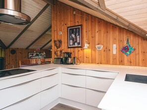 Una cocina con armarios blancos, una campana extractora de acero inoxidable, una cafetera y un cuadro en la pared.
