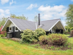 Une maison à deux étages, dotée d’une cheminée, d’un porche couvert et d’un jardin bien entretenu.