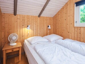 A wooden cabin room with two beds, a bedside table, a fan, and a window. - 6 Person Holiday Home in Oksbol (Oksbol)