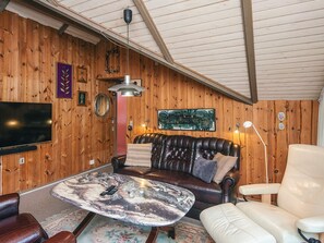 A cozy living room with a leather sofa, a white armchair, a marble coffee table, and a flat-screen TV mounted on the wall. - 6 Person Holiday Home in Oksbol (Oksbol)