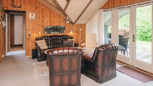 A wooden interior with a leather sofa, a white armchair, and a dining table. - 6 Person Holiday Home in Oksbol (Oksbol)