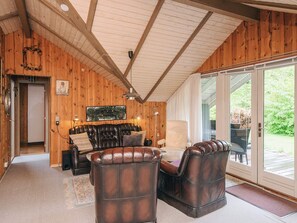 A wooden interior with a leather sofa, a white armchair, and a dining table. - 6 Person Holiday Home in Oksbol (Oksbol)