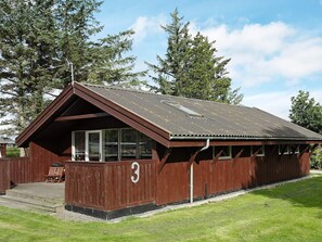 Eine Holzhütte mit Satteldach und Veranda, mit einem Schild mit der Nummer 3.
