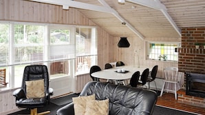 Et hyggeligt rum med en sort lædersofa, et spisebord med stole og en pejs.