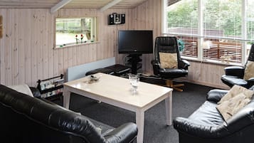 Una sala de estar acogedora con televisor, sofás de cuero, una mesa de centro y una ventana con persianas.