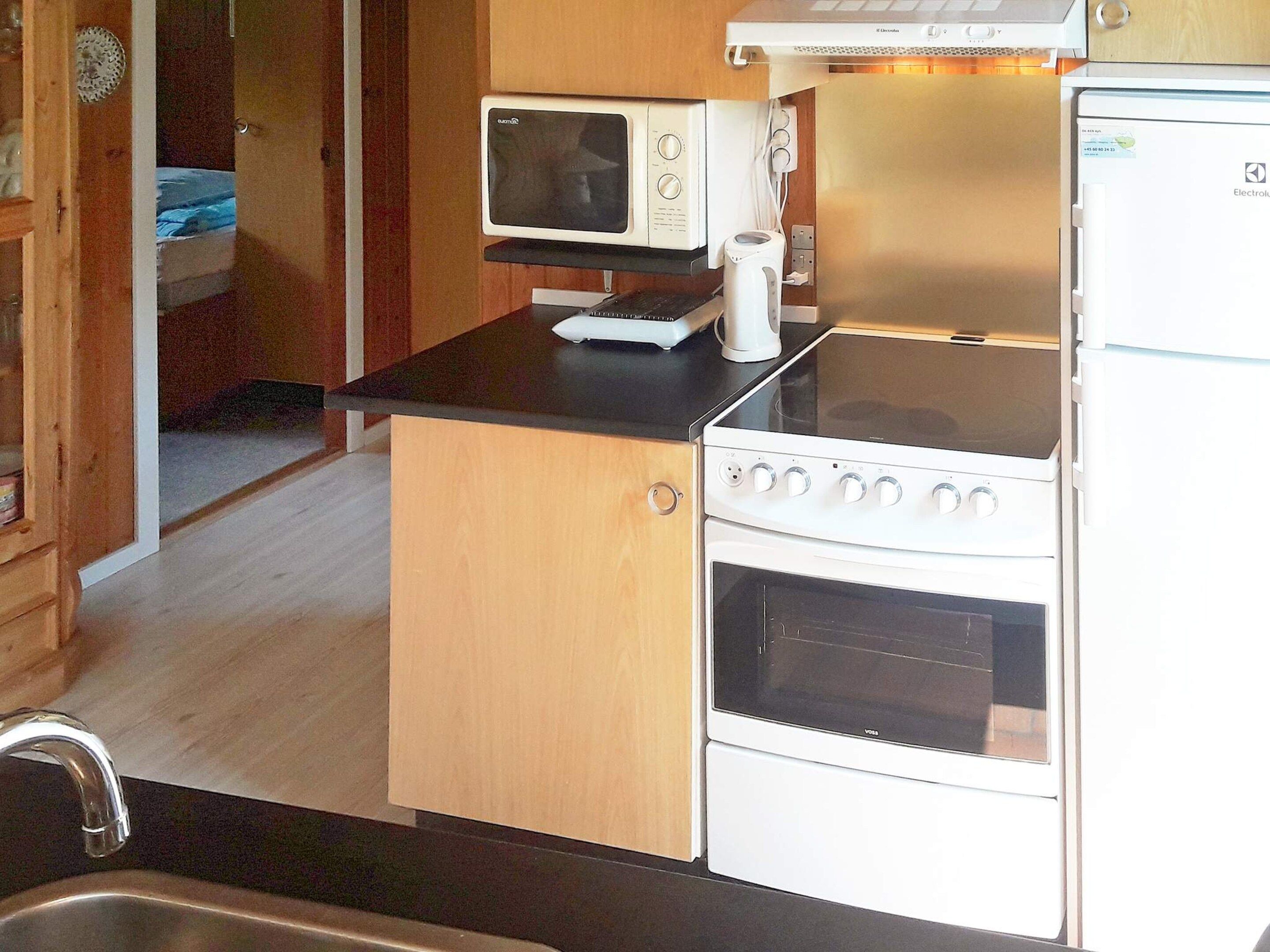 Una cucina compatta con piano cottura, forno, microonde e un piccolo ripiano.