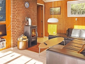 A cozy living room with a fireplace, a leather sofa, a coffee table, and a television. - 6 Person Holiday Home in Norre Nebel (Norre Nebel)